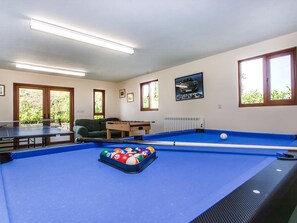 A pool table with balls, a foosball table, and a billiards table in a room with windows and a radiator. - Orchard Cottage - UKC4805 (Bishops Nympton)