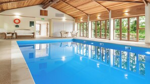 An indoor swimming pool with wooden ceiling beams, large windows, and a lifebuoy on the wall. - Barn Cottage - UKC4804 (Bishops Nympton)
