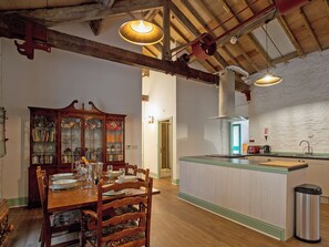 A dining area with a wooden table, chairs, and a glass cabinet. - The Old Workshop - UKC4838 (New Mills)