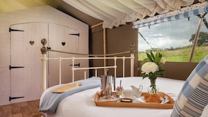 Un dormitorio acogedor con un armario de madera, una cama con una bandeja de desayuno y una ventana con vistas al campo.