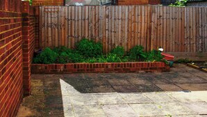 Une terrasse dallée, avec un mur en briques et une clôture en bois.