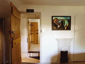 Eine offene Holztür, die zu einer Treppe, einem Kamin und einem Bild an der Wand führt.