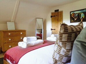 A bedroom with a bed, a wooden dresser, a mirror, and a painting on the wall. - 2 bedroom accommodation in Worstead (Worstead)