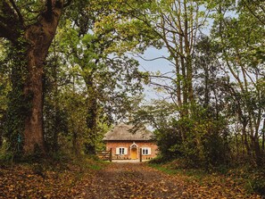 A rustic house surrounded by trees with a thatched roof and a gravel path leading to it. - 2 bedroom accommodation in Worstead (Worstead)
