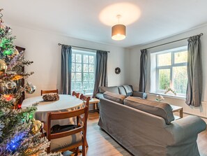 A cozy living room with a sofa, a dining table, and a Christmas tree.