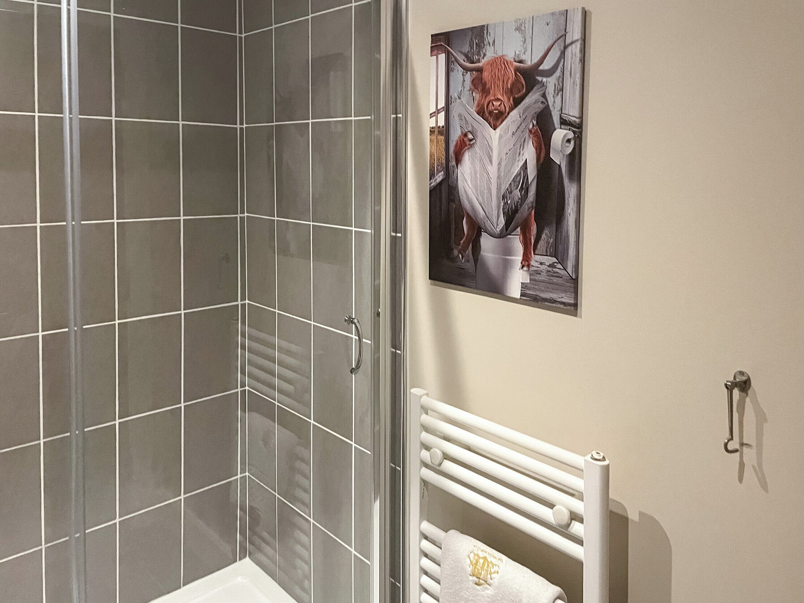 A bathroom with a shower, a toilet, and a towel rack.