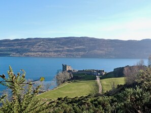 Eine historische Burg an einem See, umgeben von Hügeln.