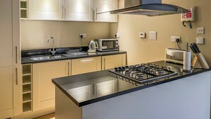 A modern kitchen with a gas stove, microwave, and sink. - Raven Wing 11 - Kintail Apartment - UKC4883 (Fort Augustus)