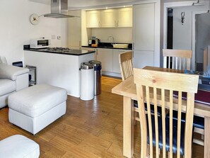 A modern kitchen with white cabinets, a microwave, and a sink. There is a wooden dining table with chairs. - Abbey Church 1 - UKC4880 (Fort Augustus)