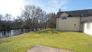 A house with a stone pathway leading to a grassy lawn beside a body of water. - Cottage 7 - Skye Cottage - ukc4884 (Fort Augustus)
