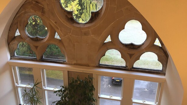A room with a large arched window featuring multiple smaller windows and a central stained glass window. - Old School 14 - UKC4893 (Fort Augustus)
