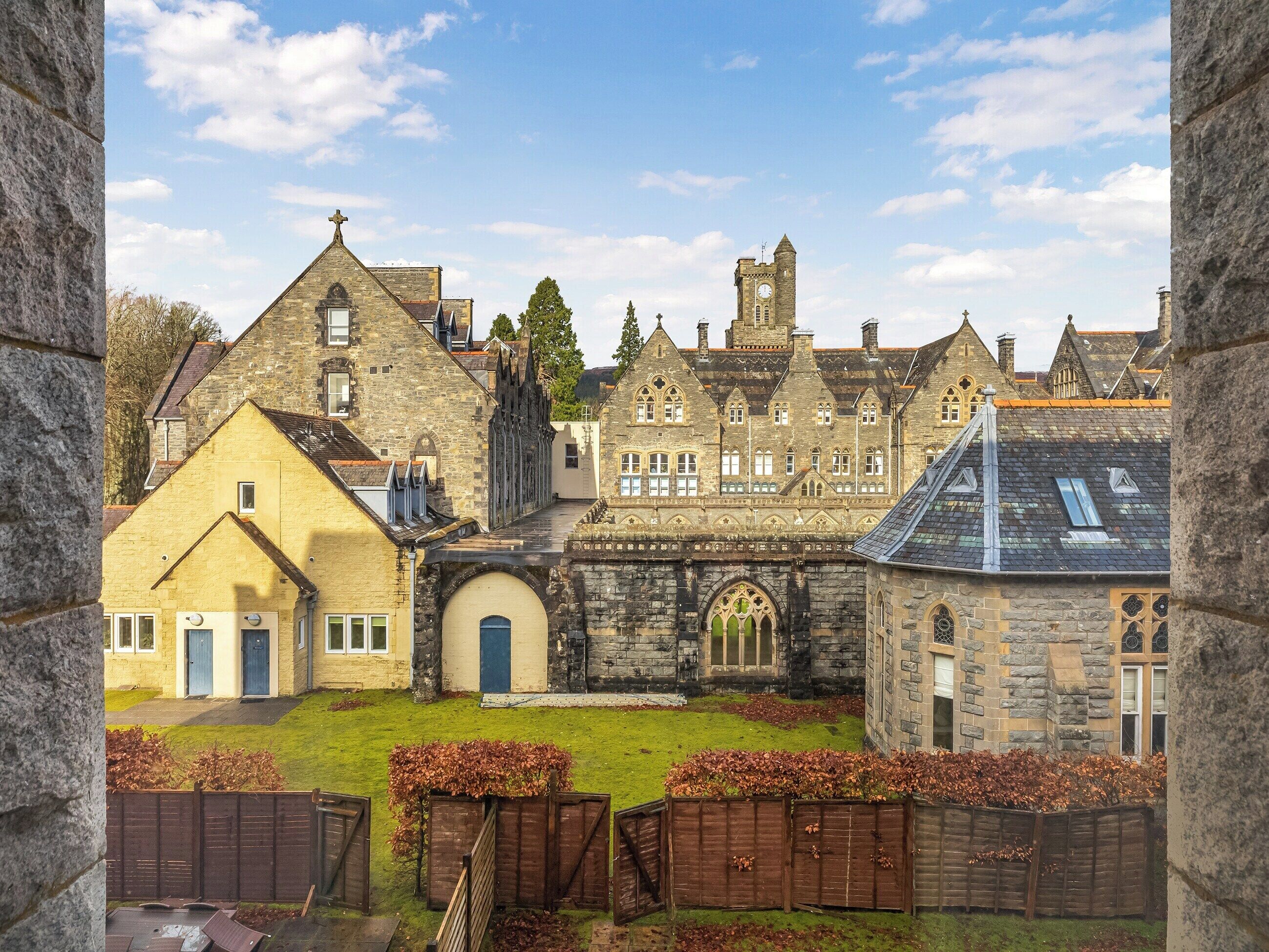 A historic building with a prominent tower, a central courtyard, and a mix of stone and brick architecture.