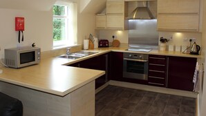 A modern kitchen with a microwave, toaster, sink, stove, and cabinets. - 2 bedroom accommodation in Invergarry (Invergarry)