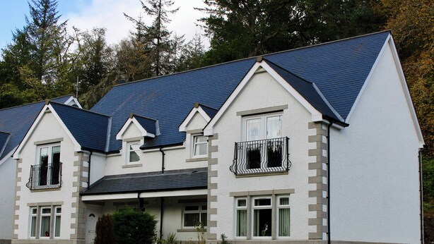A two-story house with a steeply pitched roof, a front porch, and a small front yard with potted plants. - 2 bedroom accommodation in Invergarry (Invergarry)