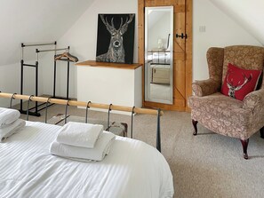 A bedroom with a bed, a chair with a deer pillow, a wooden dresser, a mirror, and a ballet barre. - 2 bedroom accommodation in Fort Augustus (Fort Augustus)