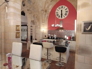 A bar area with a large clock, bar stools, and a tiled backsplash. - St Andrew's Church - UKC4890 (Fort Augustus)