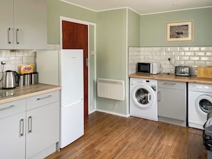 A compact kitchen with a refrigerator, microwave, toaster, and washing machine.