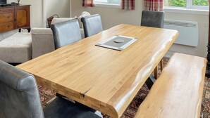 Une salle à manger avec une table en bois, des chaises à revêtement gris, un banc et un tapis à motifs.