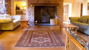 Un salon chaleureux avec une cheminée en pierre, des meubles en bois et un tapis à motifs.