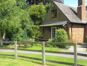 A traditional stone building with a pitched roof, a wooden fence, and a bench in front. - 2 bedroom accommodation in Timberscombe, near Minehead (Timberscombe, near Minehead)