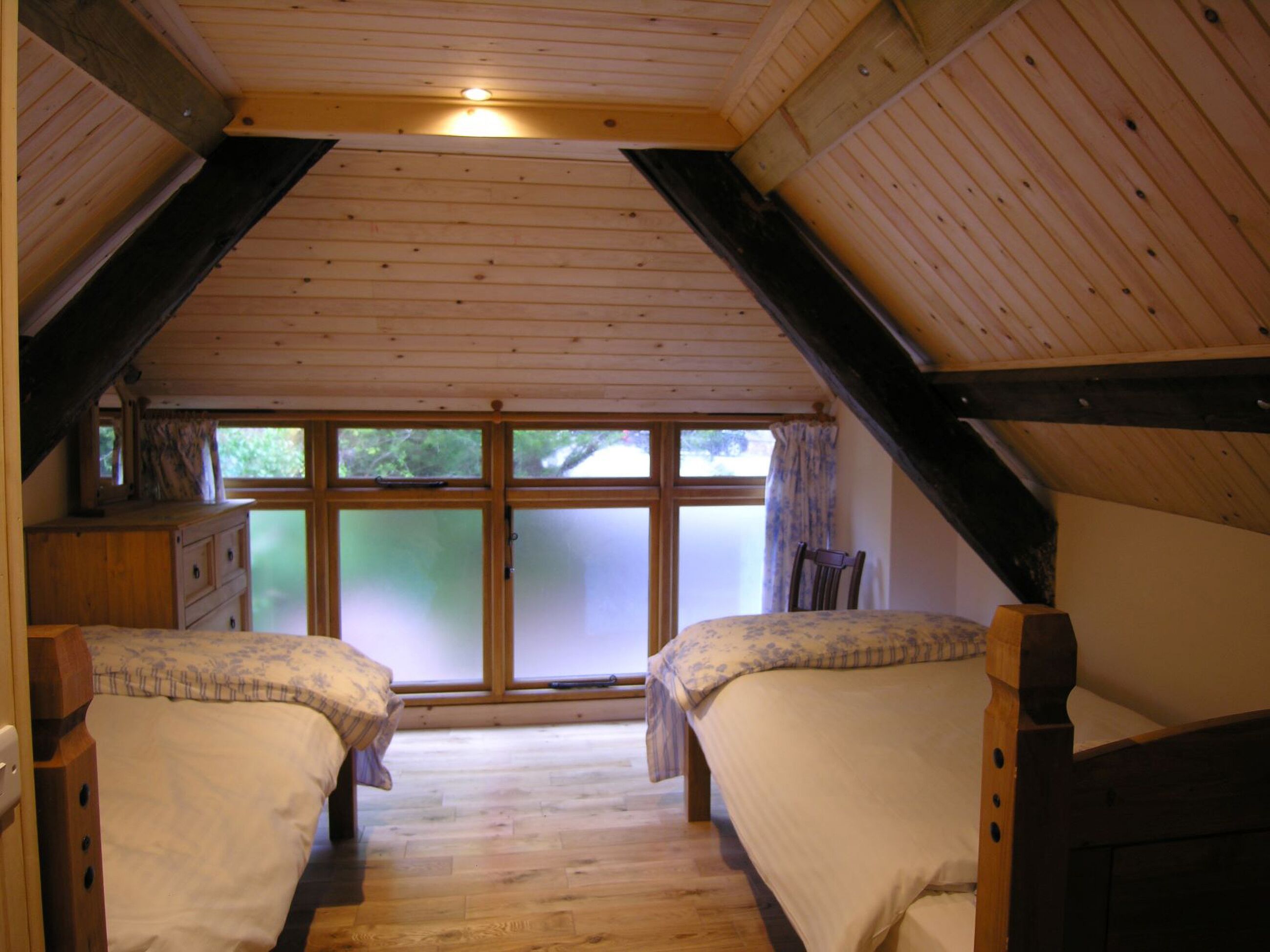 Un dormitorio con dos camas, un aparador y una ventana con cortinas.