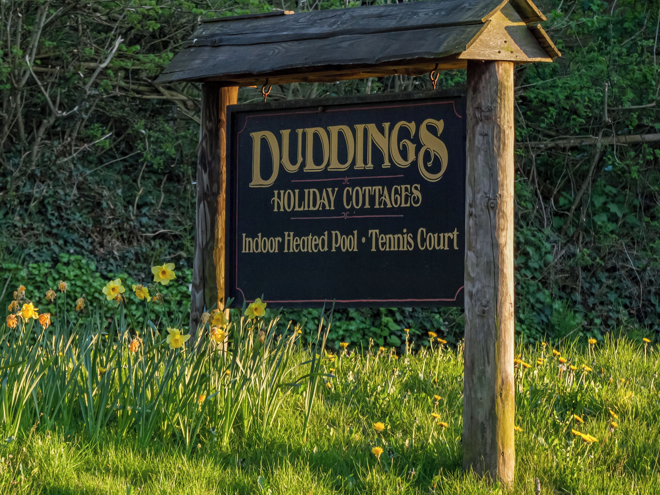 A sign for Duddings Holiday Cottages advertising an indoor heated pool and tennis court.