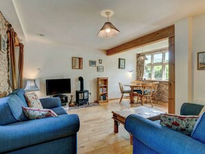 Ein Wohnzimmer mit einer Couch, einem Fernseher, einem Kamin, einem Esstisch und Bücherregalen.
