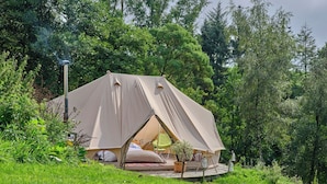 Eine Zelthütte mit flachem Dach, einer kleinen Terrasse und einem Lampenpfahl.
