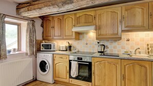 Una cocina con armarios de madera, lavadora, microondas y horno Bosch.