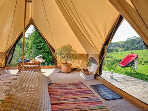 A cozy tent with a bed, a small table, a potted plant, a chair, and a view of a green landscape. - 1 bedroom accommodation in West Anstey (West Anstey)