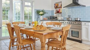 Uma cozinha com uma mesa de jantar posta para quatro pessoas, fogão, micro-ondas e coifa.