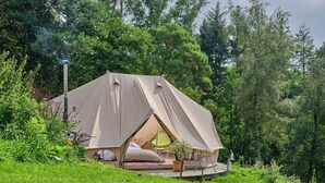 Eine Zelthütte mit flachem Dach, einer kleinen Terrasse und einem Lampenpfahl.