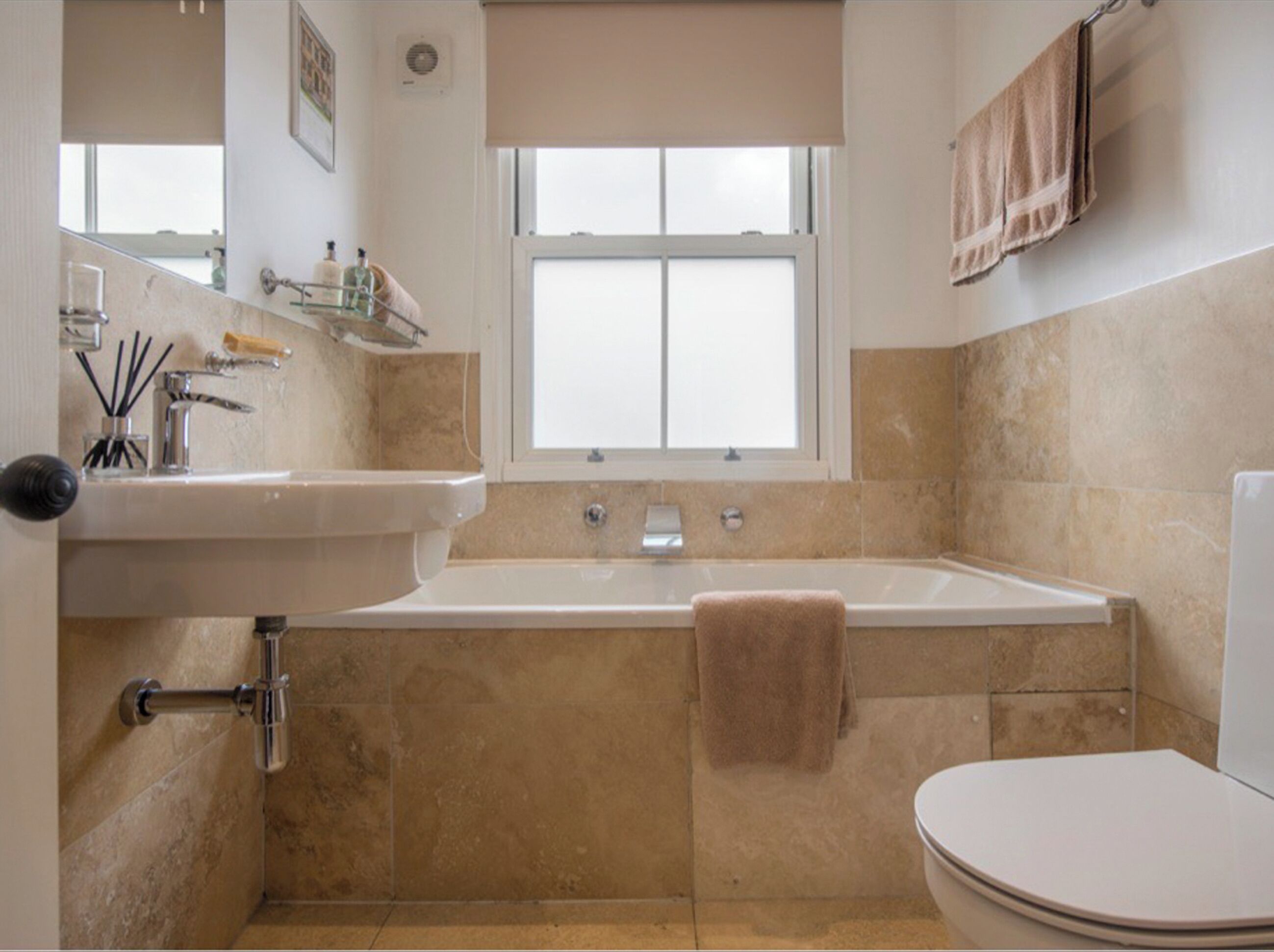 A bathroom with a bathtub, toilet, sink, and window.