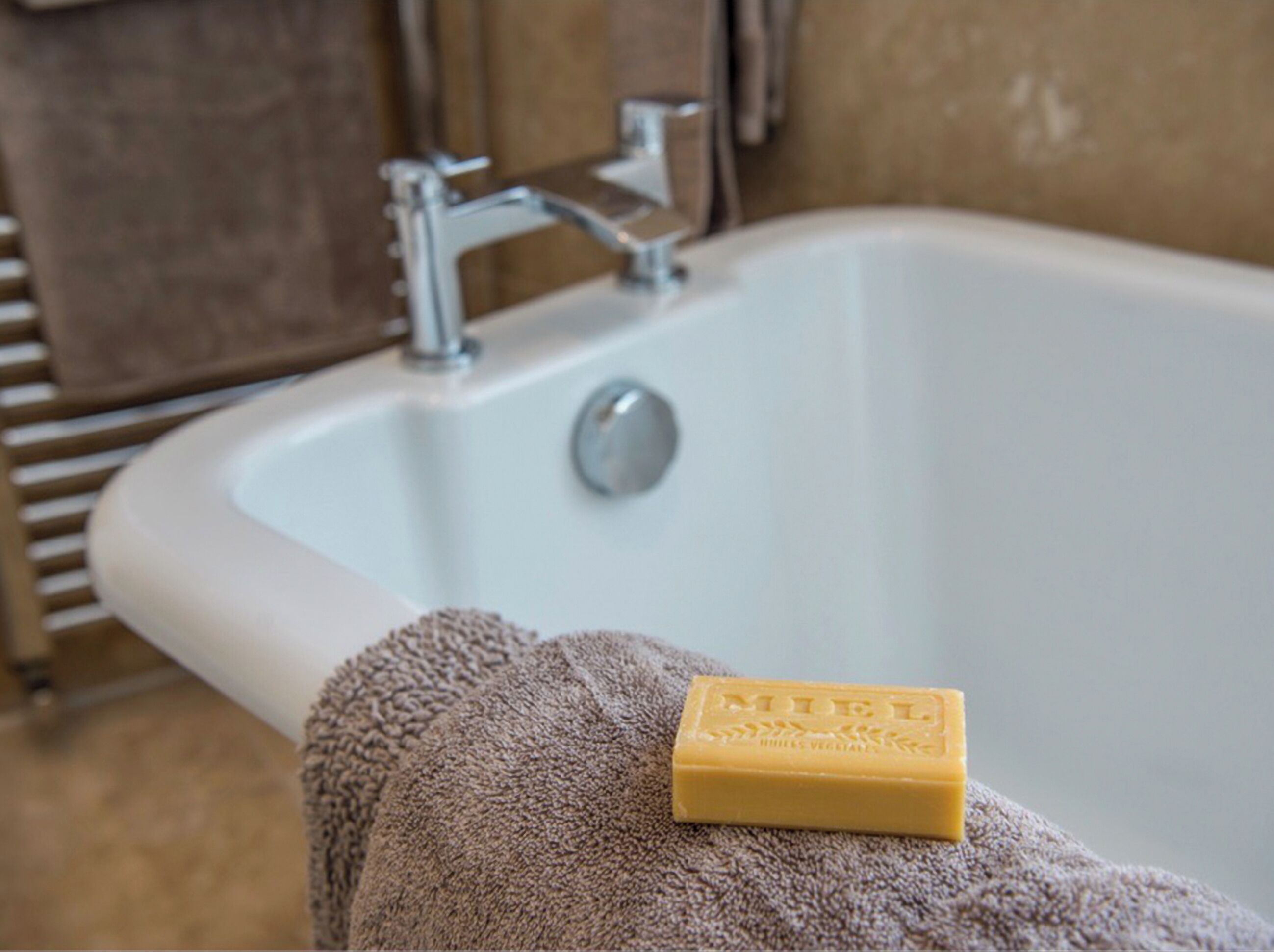 A bathroom with a white bathtub, a towel, and a bar of soap.