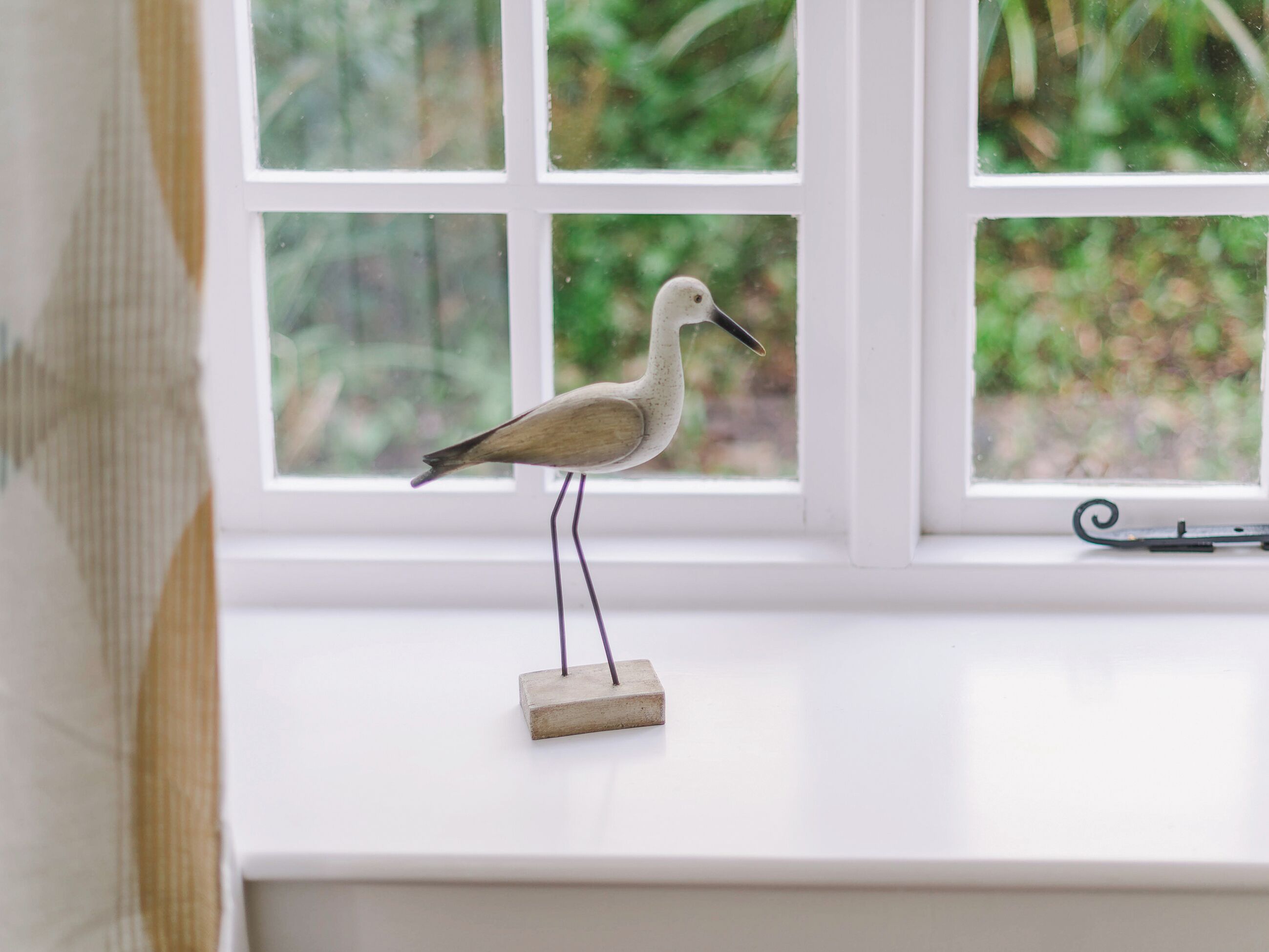 A decorative bird sculpture on a windowsill.