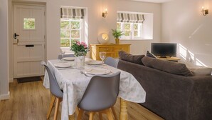 Un coin repas avec une table dressée pour quatre personnes, un canapé et un téléviseur dans le salon.