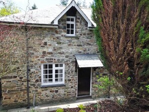 A stone building with a gabled roof, a small window, and a door. - Number One - UKC4963 (Tawstock, near Barnstaple)