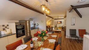 A modern kitchen with a dining area, wooden flooring, and a chandelier. - Number One - UKC4963 (Tawstock, near Barnstaple)