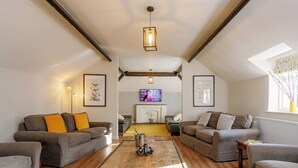A spacious living room with a wooden coffee table, two sofas with cushions, a fireplace, and a television. - Number One - UKC4963 (Tawstock, near Barnstaple)