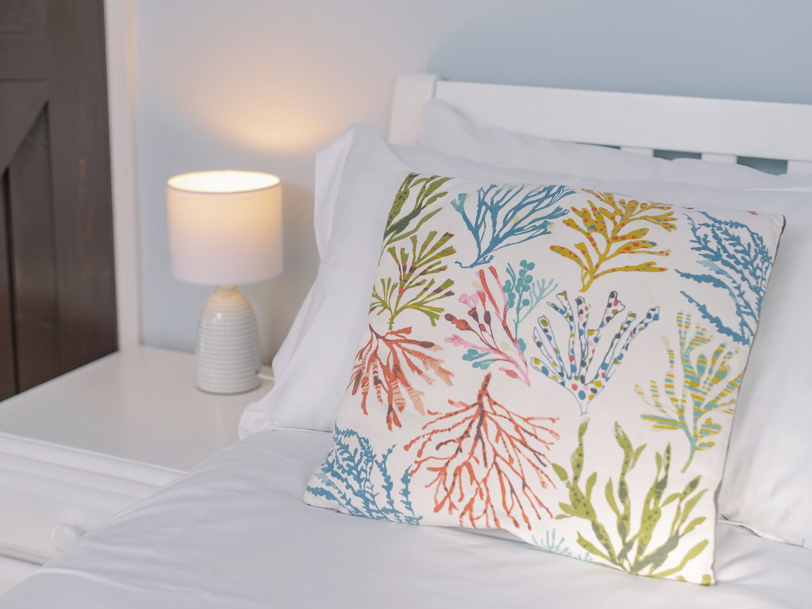 Een bed met een wit kussen met kleurrijke koraalmotieven.