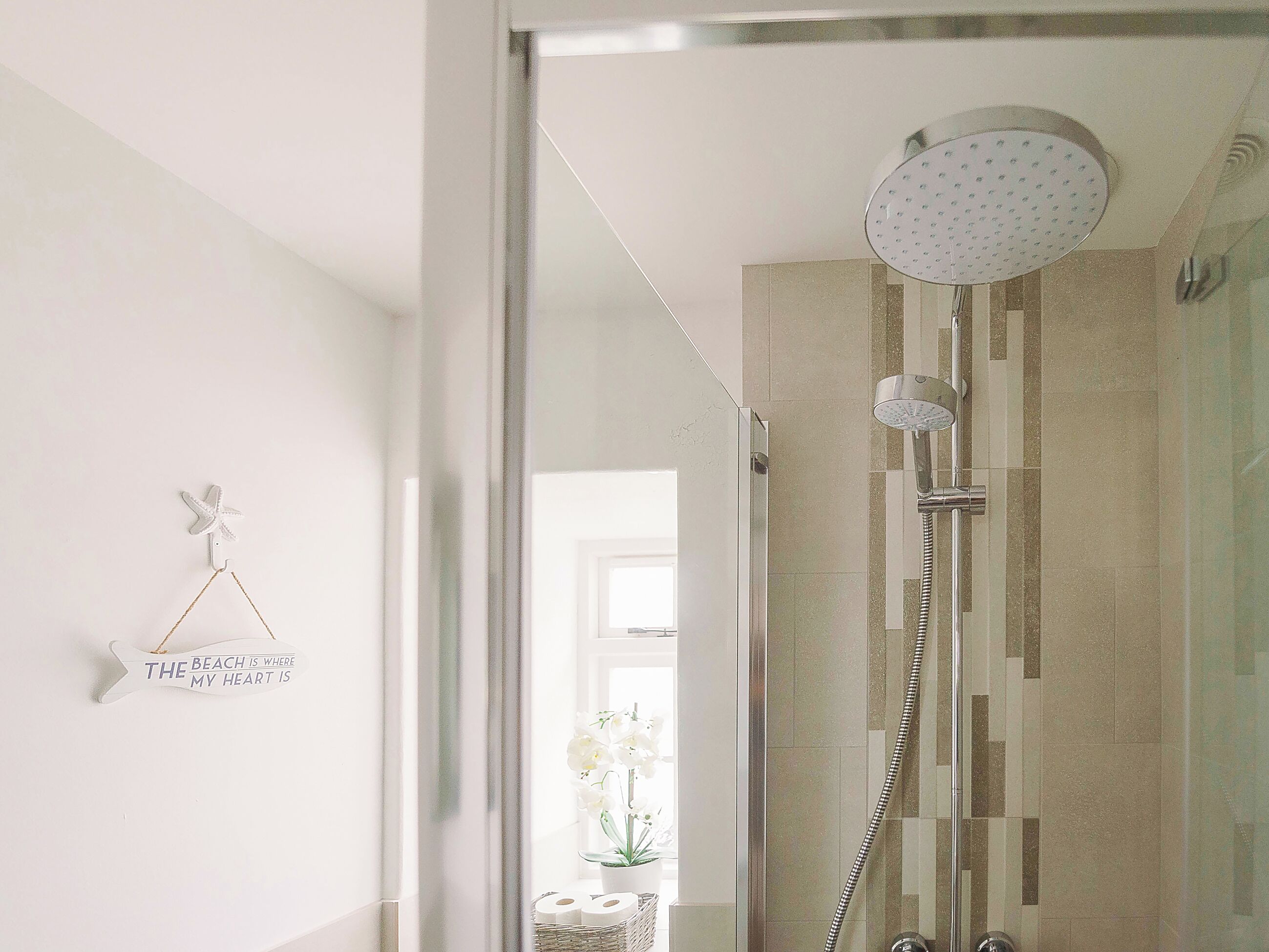 Une salle de bain moderne avec une douche à parois de verre, un porte-serviettes agrémenté d’un objet décoratif et un panneau fixé au mur.