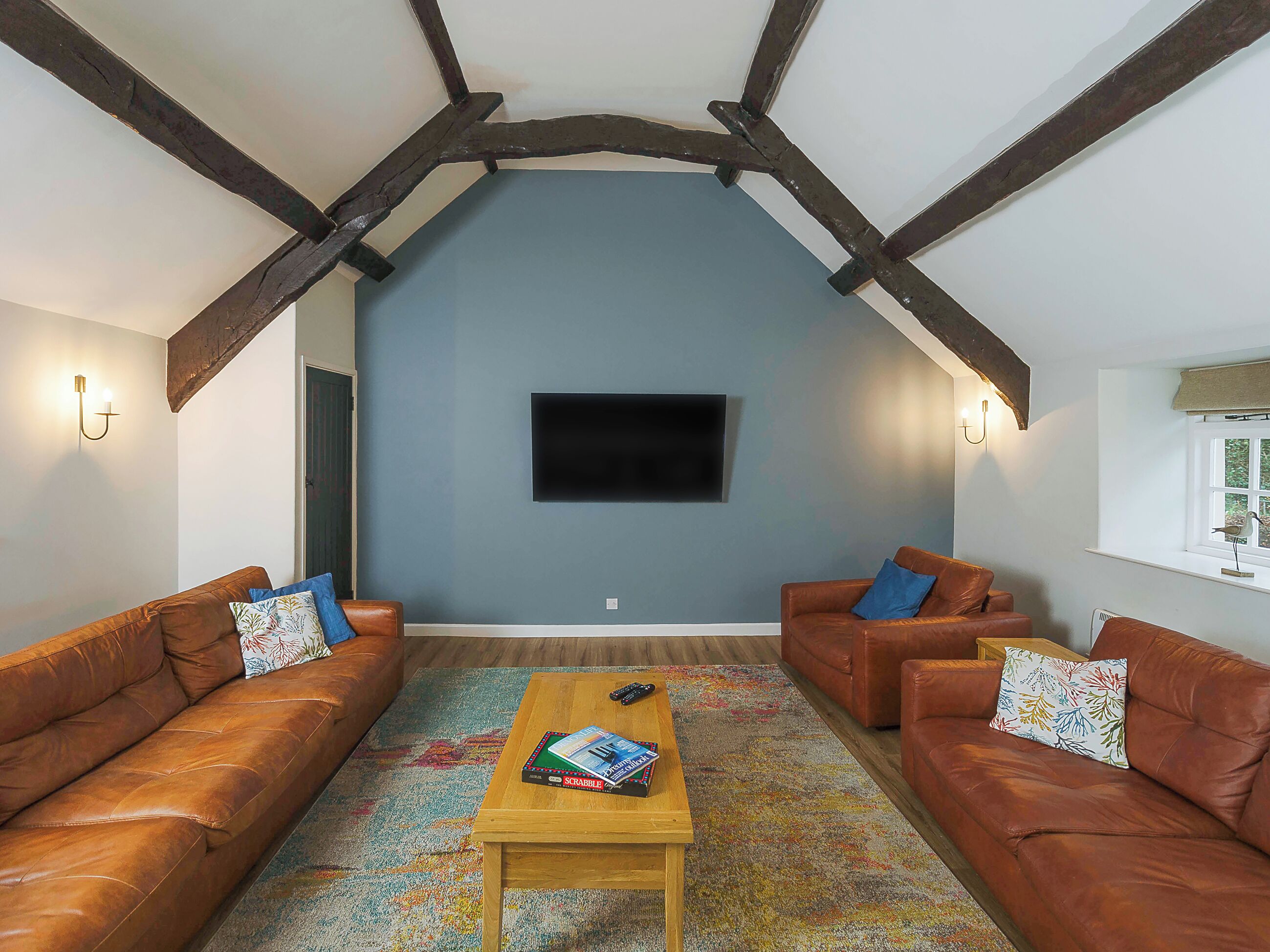 Ein gemütliches Wohnzimmer mit zwei Ledersofas, einem Couchtisch und einem an der Wand montierten Flachbildfernseher.