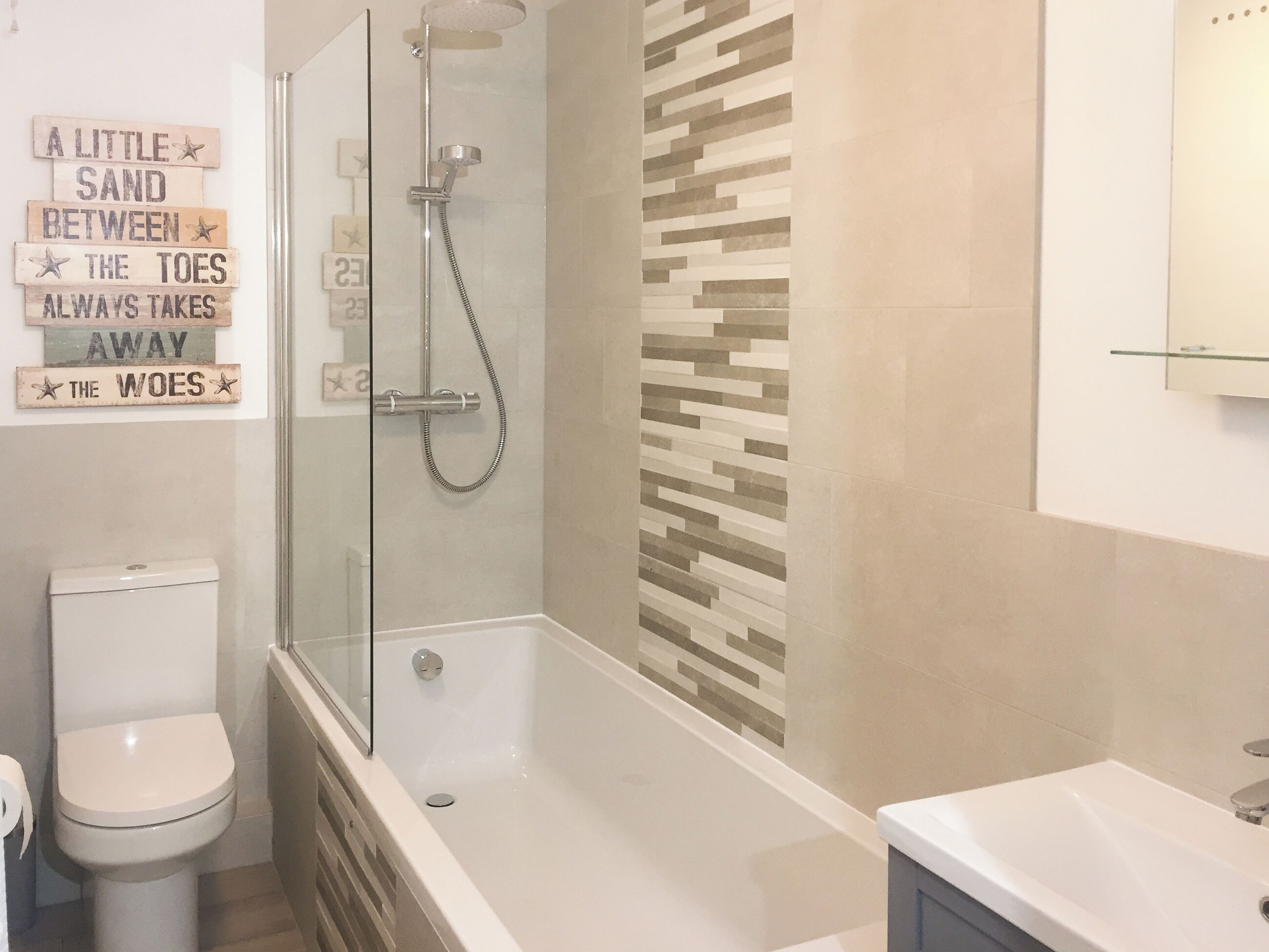 Ein modernes Badezimmer mit einer gläsernen Duschkabine, einer Toilette und einem Waschbecken.