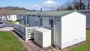 A mobile home with a porch and a small attached garage. - 3 bedroom accommodation in Dawlish Warren (Dawlish Warren)
