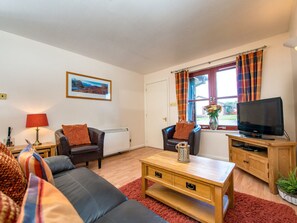 A living room with a sofa, two armchairs, a coffee table, a television, and a window with curtains. - Munro View - UKC5040 (Aviemore)