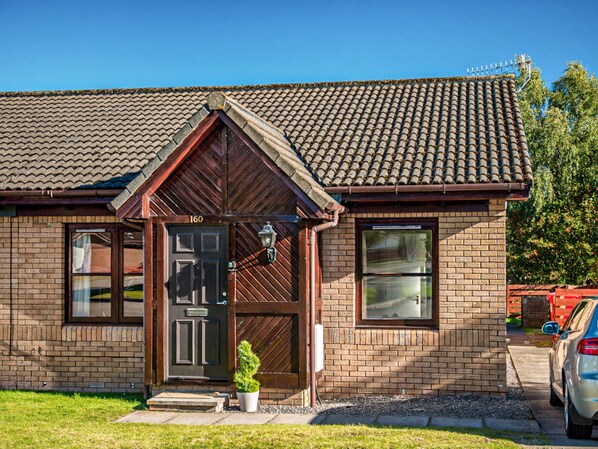 A two-story brick house with a tiled roof, a wooden front door, and a small front yard. - Munro View - UKC5040 (Aviemore)