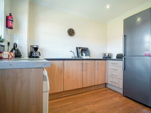 A modern kitchen with wooden cabinets, a stainless steel refrigerator, a coffee maker, and a toaster. - Birchdale Cottage - UKC5049 (Aviemore)