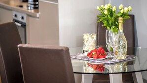 A modern dining table with a glass top, two wine glasses, a bottle of champagne, and a plate of strawberries. - 1 bedroom accommodation in Aviemore (Aviemore)