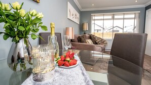 A dining table with a bottle of champagne, a glass, and a plate of strawberries. - 1 bedroom accommodation in Aviemore (Aviemore)