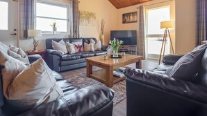 A living room with a leather sofa, a coffee table, a TV, and a lamp. - Eagle 3 Star - UKC5056 (Aviemore)